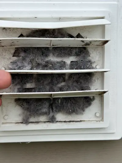 A dryer vent packed solid with lint, photographed during a maintenance visit